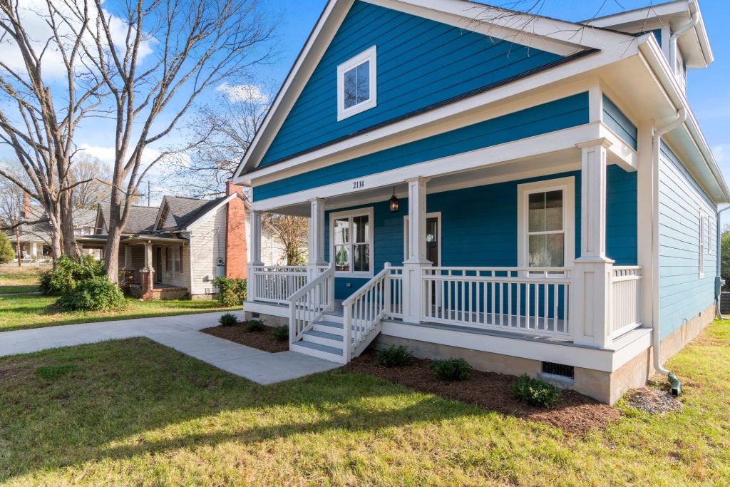 A blue house with white trim and a front porch, numbered 2114.