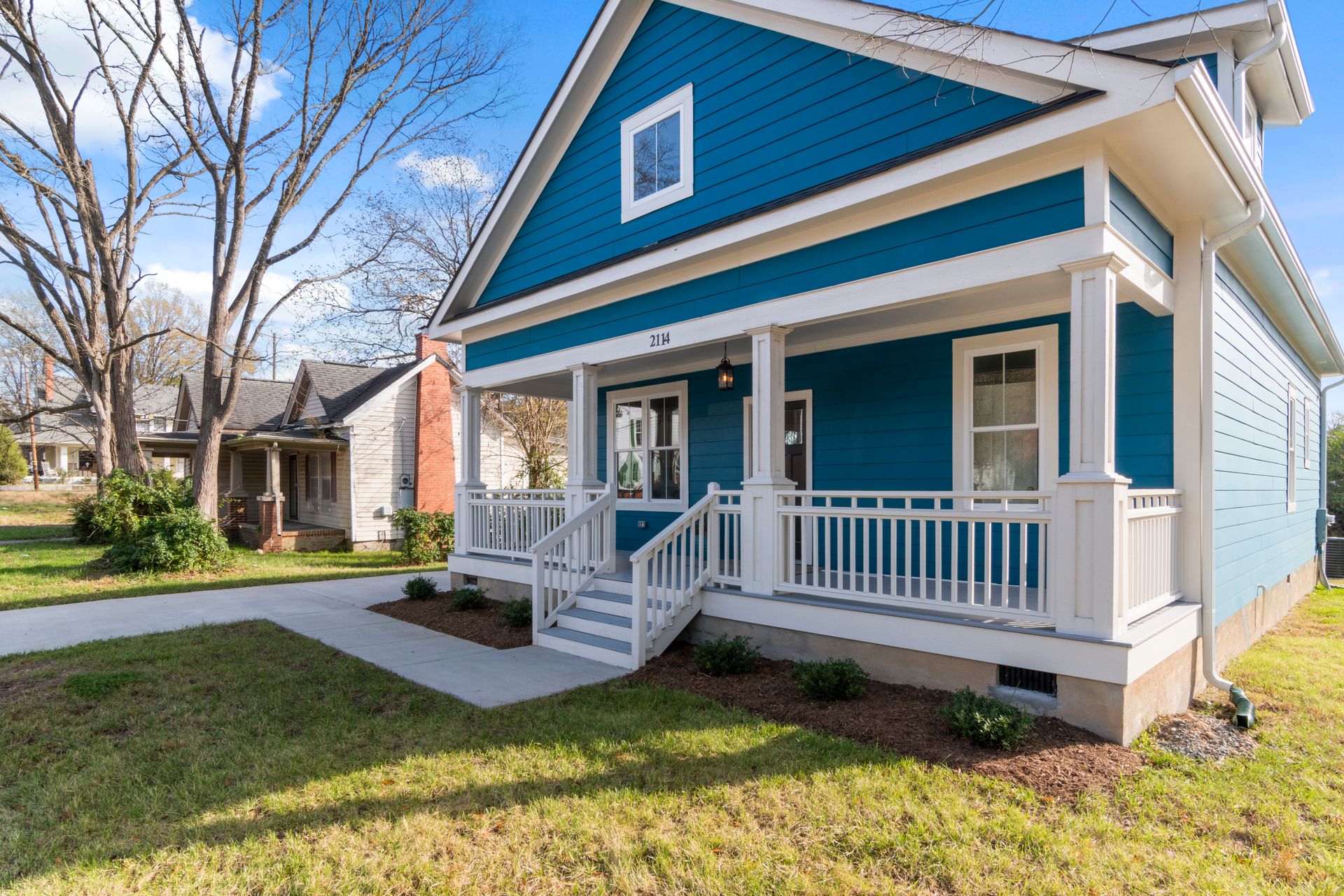 A blue house with white trim and a front porch, numbered 2114.