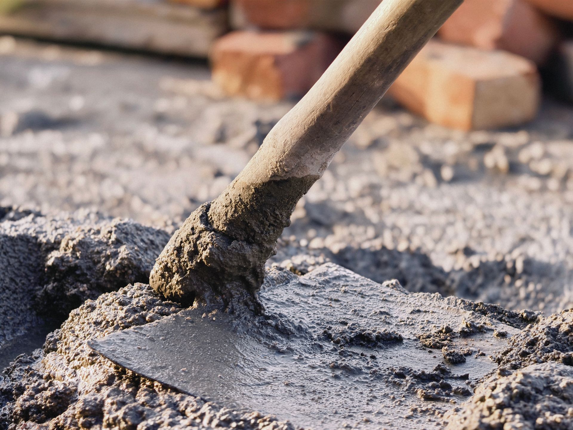 A metal hoe mixing wet concrete.